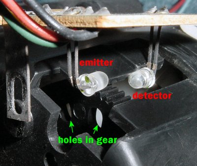 Big Trak infrared emitter and detector board pulled up slightly from the gearbox to show encoder gear with holes.