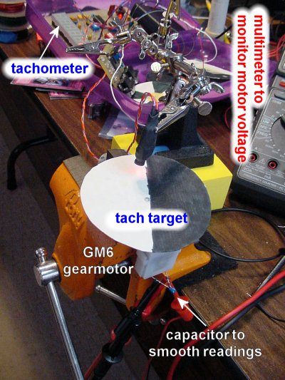 A Solarbotics GM6 gearmotor being tested with an optical tachometer and digital voltmeter.