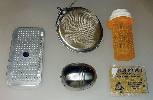 Silica gel beads in various containers such as a commercial aluminum perforated box, tea balls, and plastic containers with holes drilled in them.