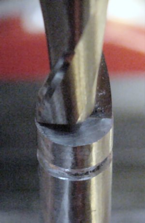 Centering a workpiece rod below the drill chuck by lining up the sides of a similar-diameter end mill.