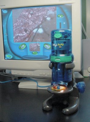 Intel QX3+ Microscope with monitor in background displaying microscope&rsquo;s view of a copper trace on the homemade circuit board