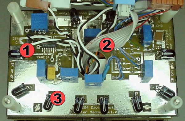 Overhead of robot sumo infrared emitter board with (1) 74AC14 38kHz wave generator, (2) center hole for cables, and (3) a bunch of IR emitters.