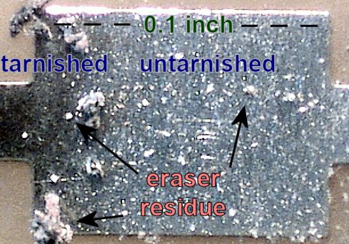 Large and small eraser residue from Pink Pearl removing tarnish from a PCB pad (60x magnification).