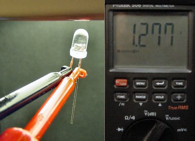 A multimeter in voltage measurement mode detects voltage in a discrete LED when held close to a light source.