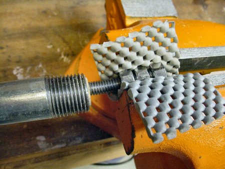Even with a rubber pad, the vise can&rsquo;t hold the nuts well enough to straighten the bent screw with this setup.