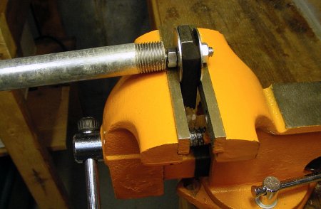 The front and back flat square jaws of the vise securely hold one end of the bent screw while force is applied by a steel pipe.