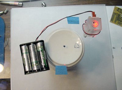 DIY laser level made from a clear plastic plate, laser pen PCB, AA batteries, and an overhead transparency.