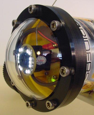 Clear plastic dome bolted to a black plastic collar to protect a wireless video camera and other electronics.