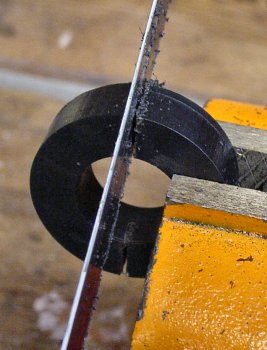 Cutting a plastic ring in half with a hacksaw.