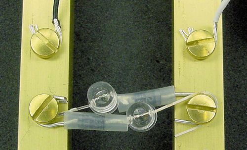 Brass rails and screws hold wires and dual blinking LEDs with reverse polarity diode protection.