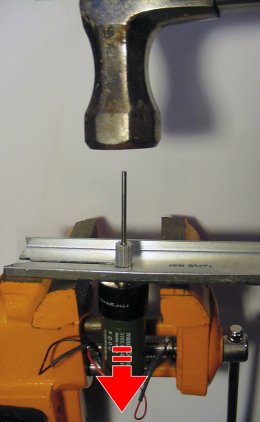 Tapping the rod with a hammer to force the motor shaft free from a gear.