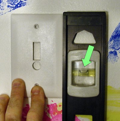 The outline of the custom wall plate holes are traced with a pencil after lining up the plate with a spirit level.